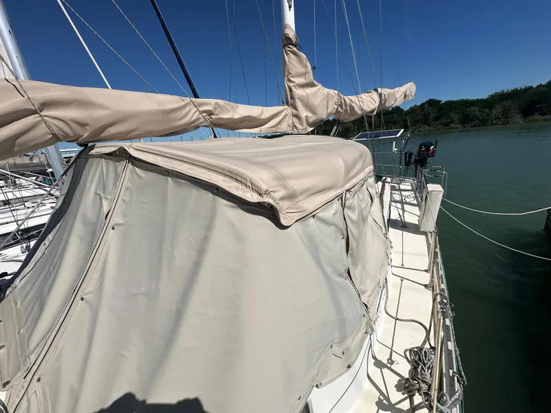 Slide: The Image of 1981 Islander Freeport Ketch sailboat with beige cover, docked on a sunny day. - 18