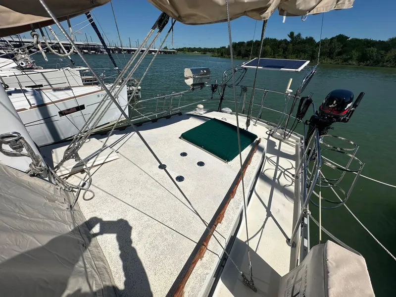 Slide: The Image of 1981 Islander Freeport Ketch sailboat deck with solar panel and outboard motor, docked by a river. - 19