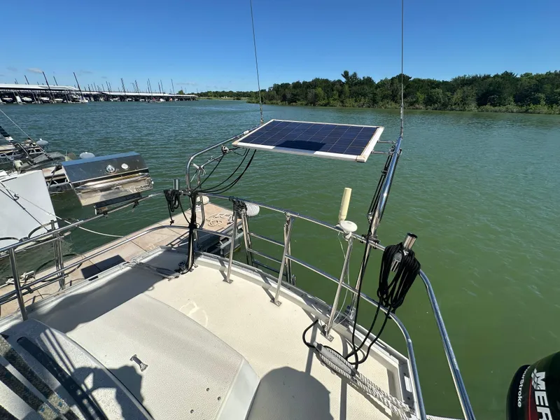 Slide: The Image of 1981 Islander Freeport Ketch with solar panel, docked on a serene river. - 20