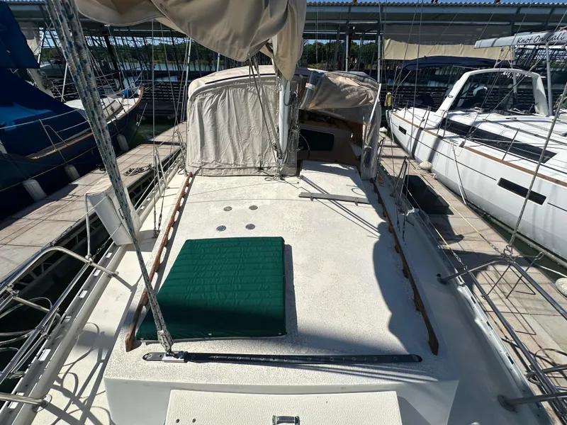 Slide: The Image of 1981 Islander Freeport Ketch sailboat deck with green cushion, docked at marina. - 21