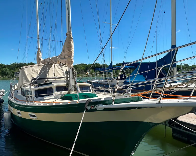 Slide: The Image of 1981 Islander Freeport Ketch sailboat docked in marina under clear blue sky. - 24