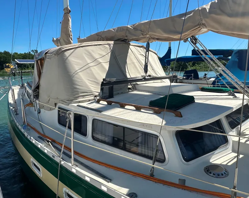 Slide: The Image of 1981 Islander Freeport Ketch sailboat docked, featuring beige canopy and green accents. - 26