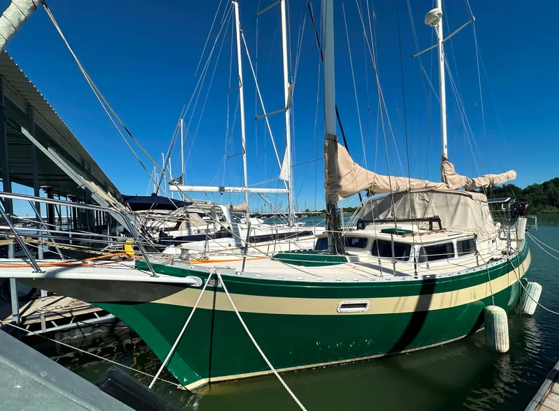 Slide: The Image of 1981 Islander Freeport Ketch sailboat docked, green hull, beige sails, clear blue sky. - 3