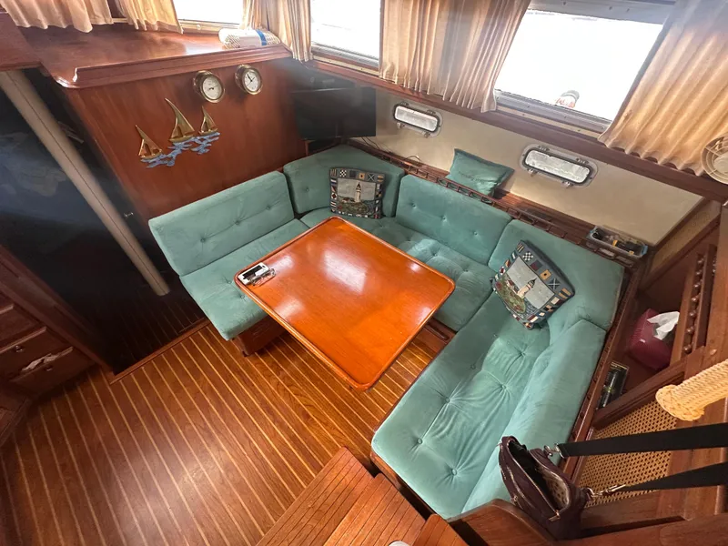 Slide: The Image of 1981 Islander Freeport Ketch interior with teal seating, wooden table, and nautical decor. - 37