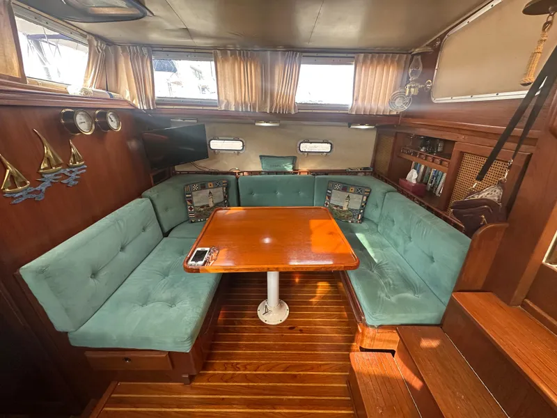 Slide: The Image of 1981 Islander Freeport Ketch interior with teal seating, wooden table, and nautical decor. - 38