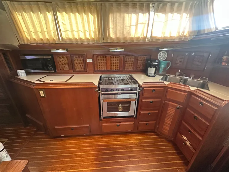 Slide: The Image of 1981 Islander Freeport Ketch kitchen with wooden cabinetry, stove, and sink, featuring natural light. - 39