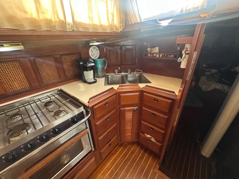 Slide: The Image of 1981 Islander Freeport Ketch kitchen with stove, sink, and wooden cabinetry. - 40