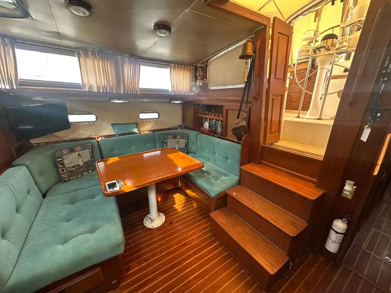 Slide: The Image of Interior of 1981 Islander Freeport Ketch with teal seating, wooden table, and stairs. - 41