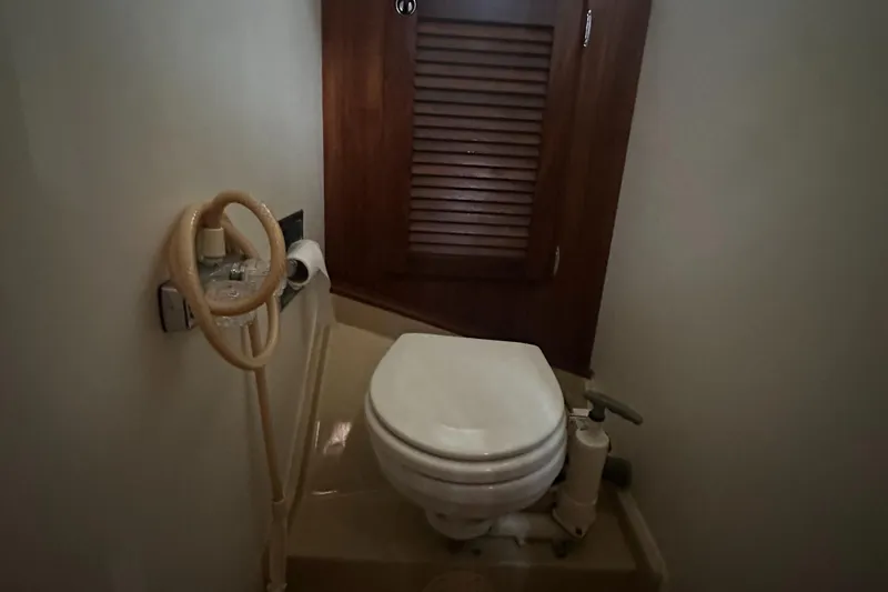 Slide: The Image of 1981 Islander Freeport Ketch bathroom with toilet, wooden cabinet, and nautical decor. - 42