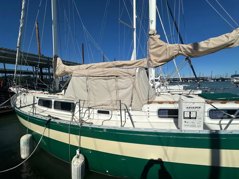 Slide: The Image of 1981 Islander Freeport Ketch sailboat docked, featuring green and white hull with covered sails. - 6