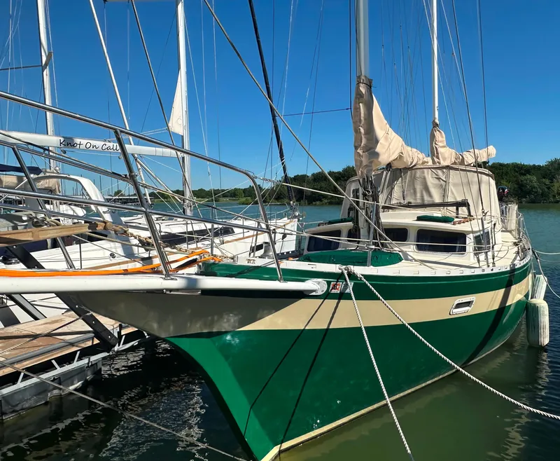 Slide: The Image of 1981 Islander Freeport Ketch sailboat docked, green hull, beige sails, sunny day. - 7