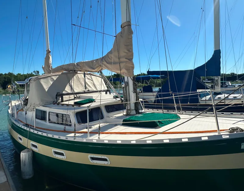 Slide: The Image of 1981 Islander Freeport Ketch sailboat docked in a marina under clear blue skies. - 8