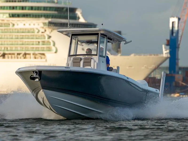 Slide: The Image of 2025 Caymas 291 boat cruising on water with a large ship in the background. - 12