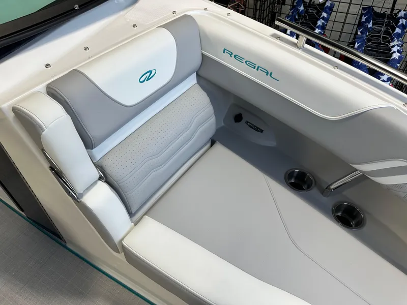 Slide: The Image of 2025 Regal LS6 boat interior with gray and white seating, featuring cup holders. - 17