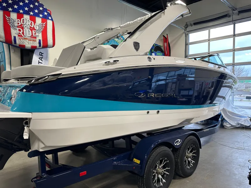Slide: The Image of 2025 Regal LS6 boat on trailer in showroom, featuring sleek blue and white design. - 2