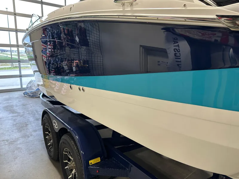 Slide: The Image of 2025 Regal LS6 boat on trailer in showroom, featuring sleek blue and white design. - 3