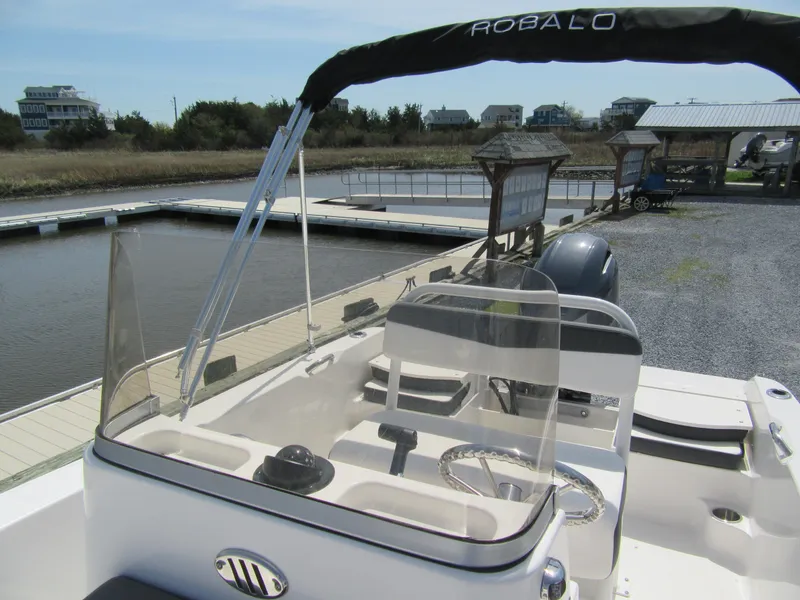 Slide: The Image of 2025 Robalo R160 Center Console boat docked by a serene waterfront. - 8