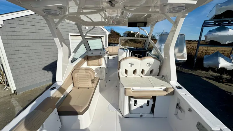 Slide: The Image of 2025 Edgewater 262CX boat interior with seating and helm, docked outdoors. - 13