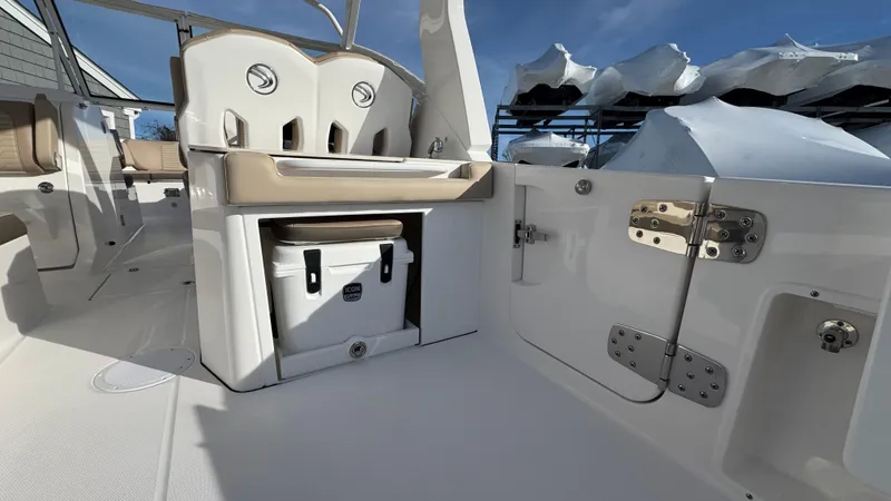 Slide: The Image of 2025 Edgewater 262CX boat interior with seating, storage, and cooler under clear blue sky. - 15
