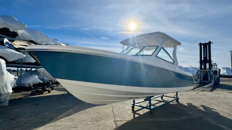 Slide: The Image of 2025 Edgewater 262CX boat under bright sun, displayed outdoors on a stand. - 2
