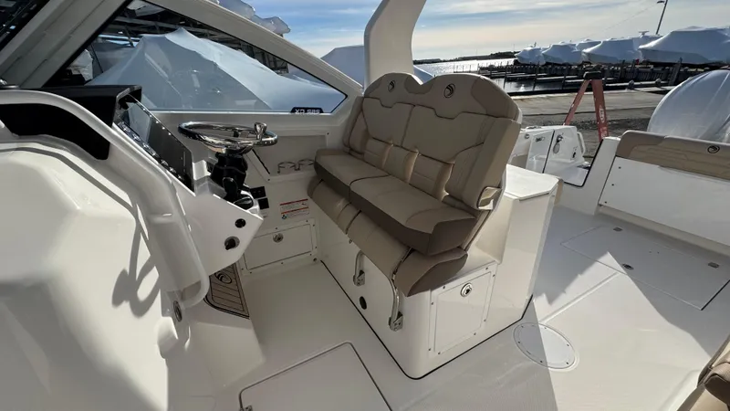 Slide: The Image of 2025 Edgewater 262CX boat interior with beige seating and modern helm controls. - 22