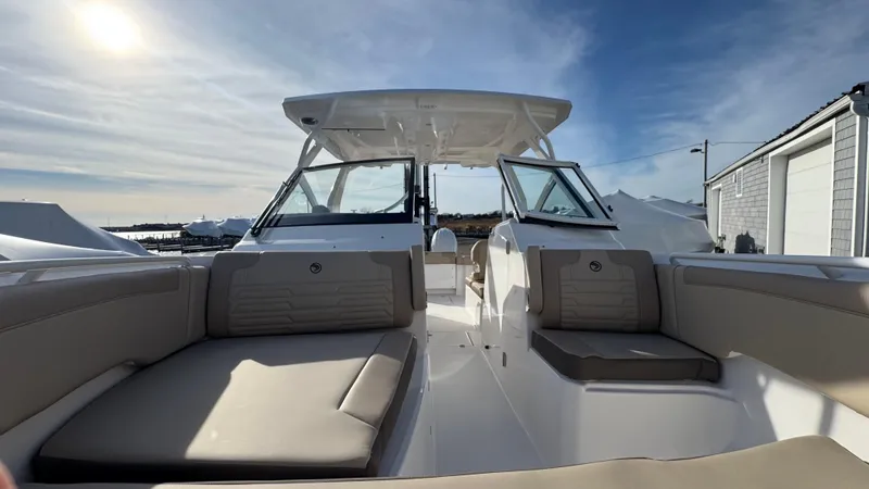 Slide: The Image of 2025 Edgewater 262CX boat interior with cushioned seating under a clear sky. - 31