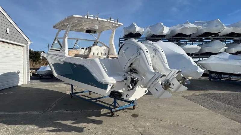 Slide: The Image of 2025 Edgewater 262CX boat with dual outboard engines on a stand, outdoor storage. - 5