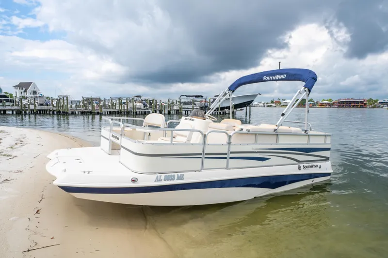 Slide: The Image of 2008 Bennington 201FS Southwind boat docked on sandy shore under cloudy sky. - 1