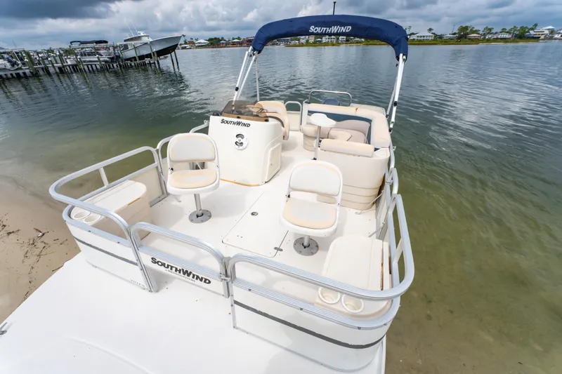 Slide: The Image of 2008 Bennington 201FS Southwind boat docked by the shore, featuring comfortable seating and a canopy. - 15