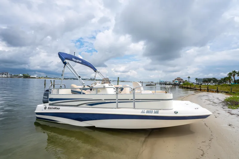 Slide: The Image of 2008 Bennington 201FS Southwind boat docked on a sandy shore under cloudy skies. - 3