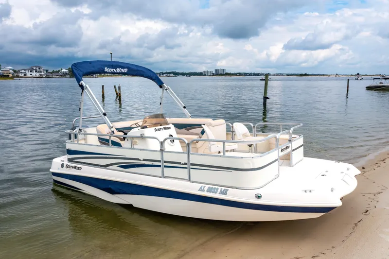 Slide: The Image of 2008 Bennington 201FS Southwind boat docked on a sandy shore under cloudy skies. - 6