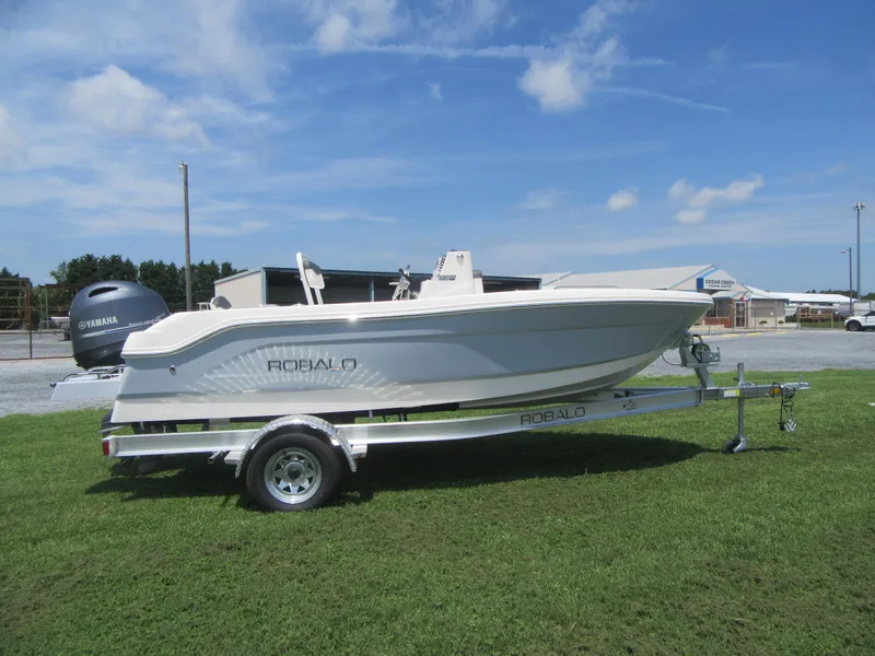 Slide: The Image of 2025 Robalo R160 Center Console boat on trailer, parked on grass under blue sky. - 2