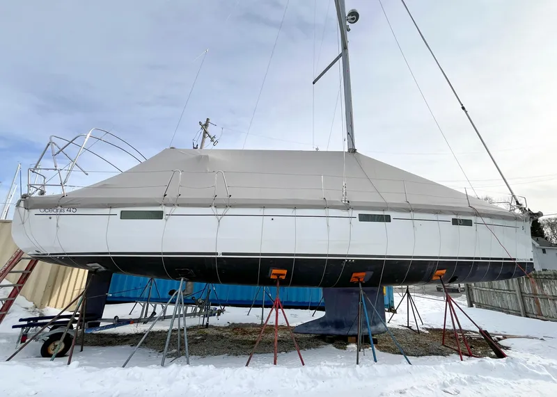 Slide: The Image of 2018 Beneteau Oceanis 45 sailboat covered and elevated on stands in a snowy yard. - 15