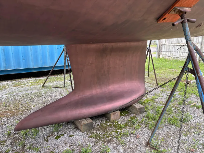 Slide: The Image of Keel of 2018 Beneteau Oceanis 45 sailboat on stands, gravel ground, blue container background. - 16