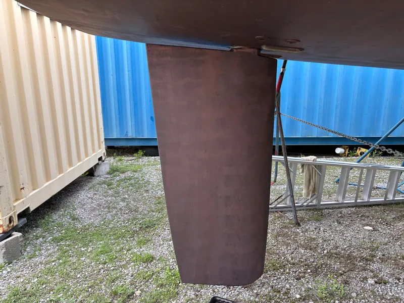 Slide: The Image of Rudder of a 2018 Beneteau Oceanis 45 sailboat, displayed outdoors near shipping containers. - 17