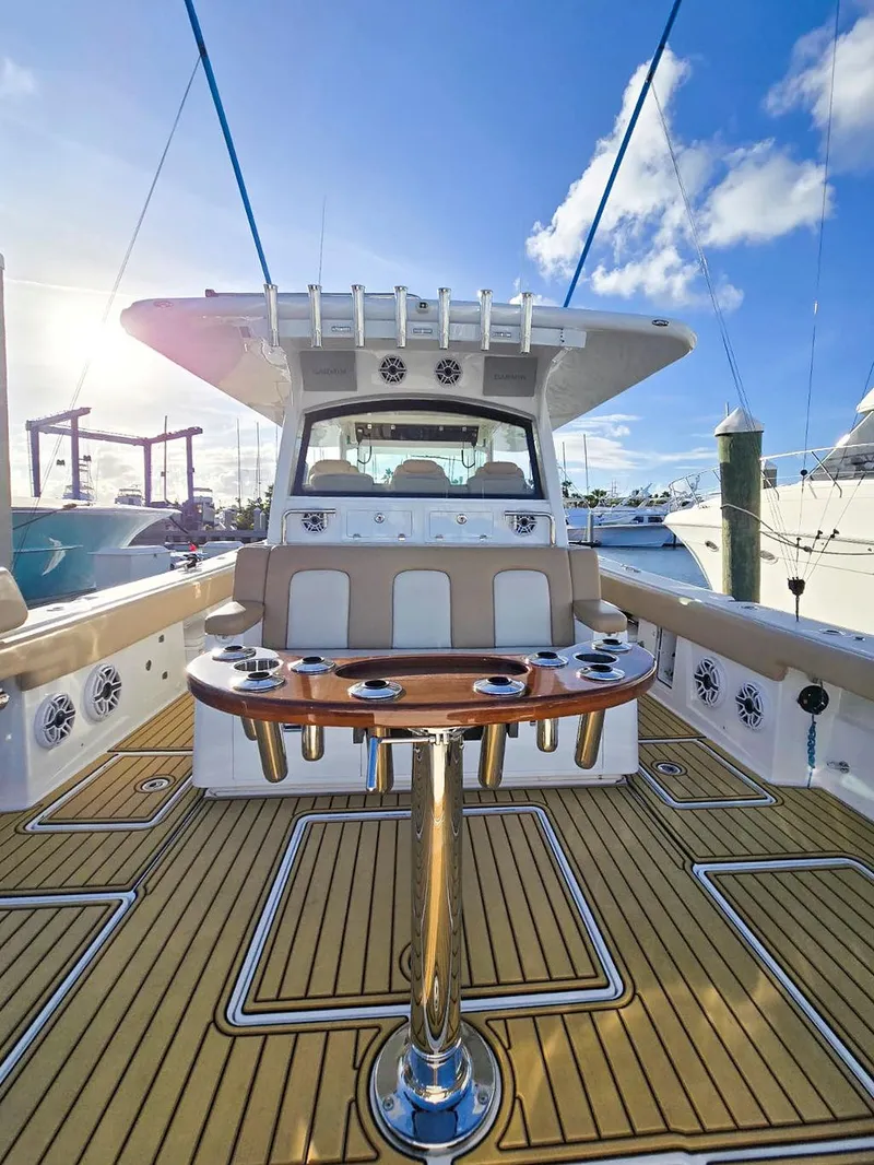 Slide: The Image of 2023 HCB Suenos boat interior with seating and rod holders, docked at a marina. - 14