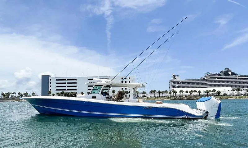 Slide: The Image of 2023 HCB Suenos boat on water, blue hull, modern design, cityscape background. - 2