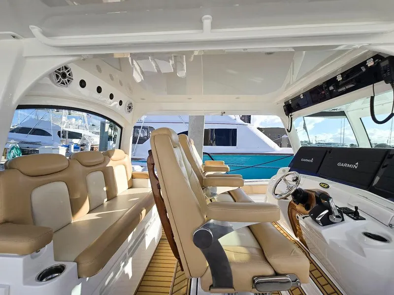 Slide: The Image of 2023 HCB Suenos boat interior with tan seats and modern dashboard at marina. - 21