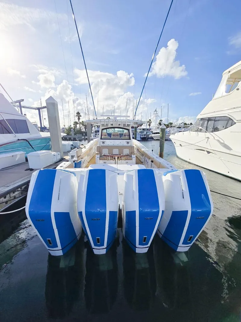 Slide: The Image of 2023 HCB Suenos boat with four blue and white outboard motors docked at a marina. - 6