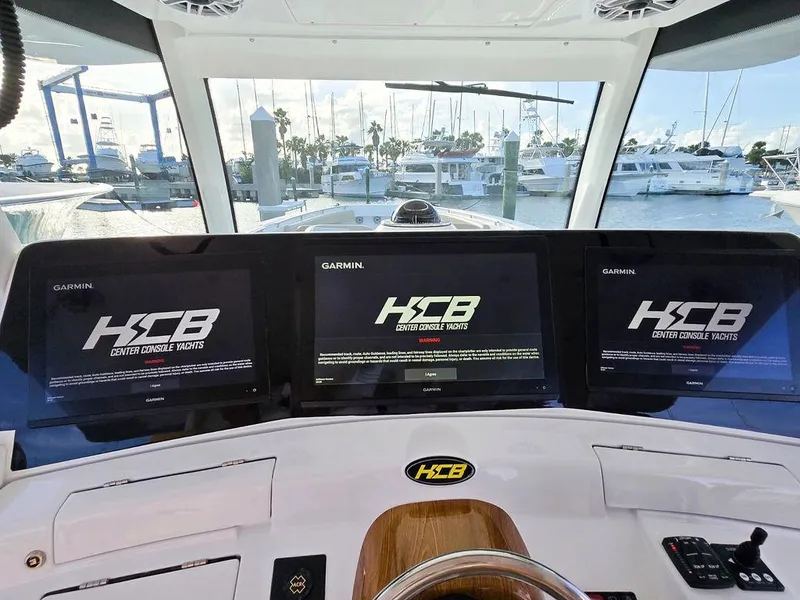 Slide: The Image of 2023 HCB Suenos boat interior with helm, docked at marina under clear sky. - 31