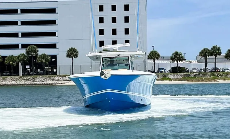 Slide: The Image of 2023 HCB Suenos boat cruising on water near a modern building. - 4