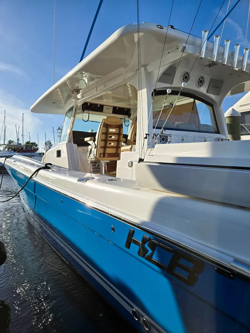 Slide: The Image of 2023 HCB Suenos boat with blue hull docked in marina under clear sky. - 7