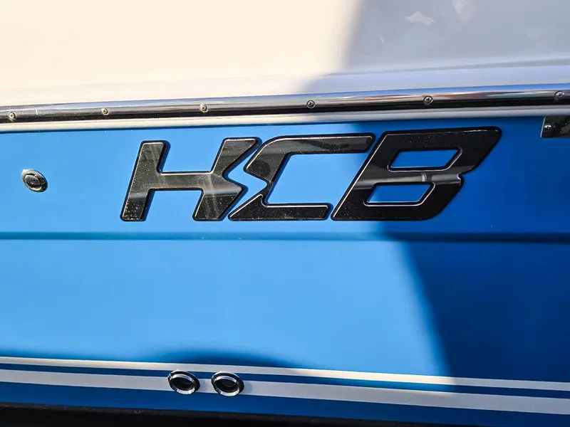 Slide: The Image of 2023 HCB Suenos boat at marina, featuring sleek deck and fishing rod holders. - 9