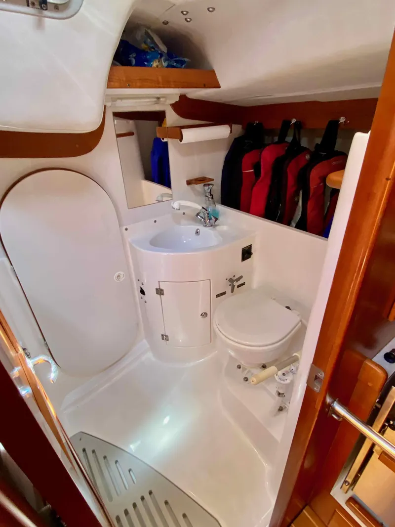 Slide: The Image of 2001 J Boats J/46 yacht bathroom with sink, toilet, and hanging jackets. - 19