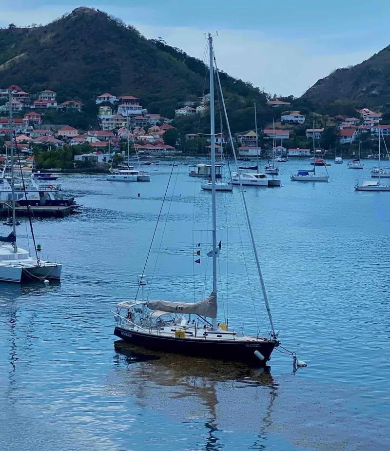 Slide: The Image of Sailboat J/46 (2001) by J Boats anchored in scenic harbor with hills and houses. - 3