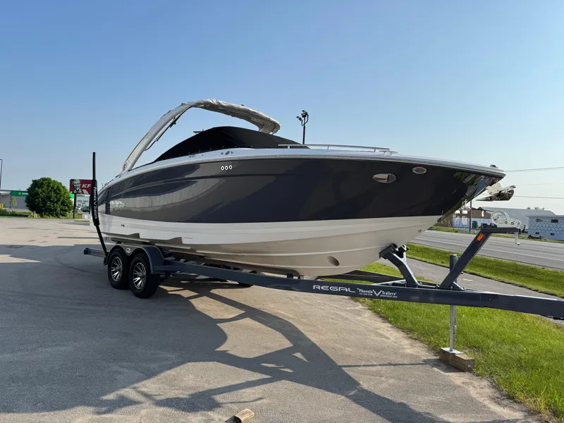 Slide: The Image of 2025 Regal LS9 Surf boat on trailer, parked outdoors under clear sky. - 1