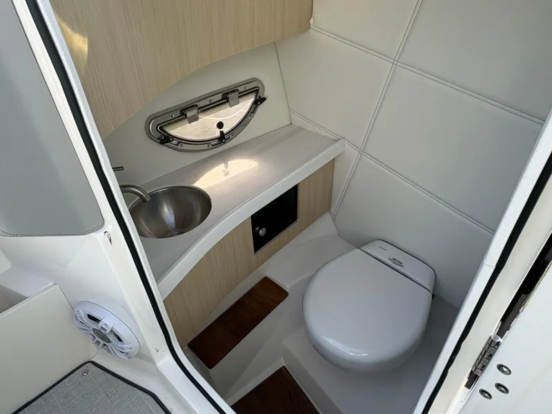 Slide: The Image of 2025 Regal LS9 Surf boat bathroom with sink, toilet, and porthole window. - 25
