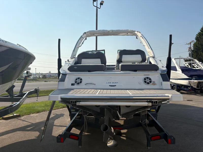 Slide: The Image of 2025 Regal LS9 Surf boat, rear view, parked outdoors, showcasing swim platform and seating. - 3