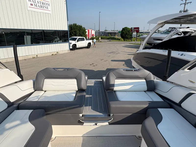 Slide: The Image of 2025 Regal LS9 Surf boat interior with gray and white seating at a marina. - 35