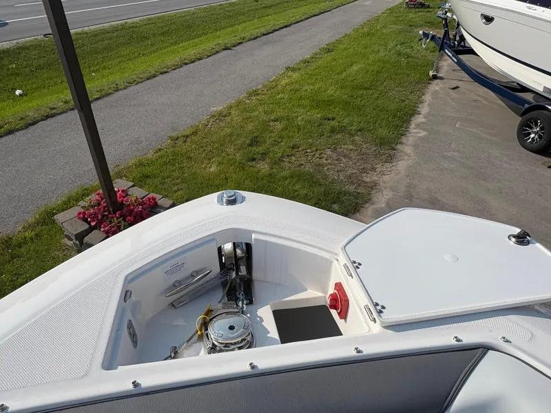Slide: The Image of 2025 Regal LS9 Surf boat bow with open storage compartment, parked on a paved area. - 5